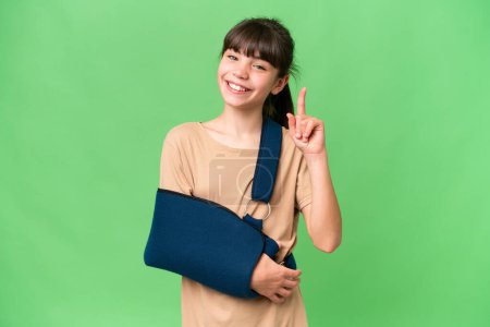 Photo for Little caucasian girl with broken arm and wearing a sling over isolated background pointing up a great idea - Royalty Free Image