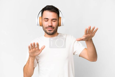 Young handsome caucasian man over isolated white background listening music and dancing
