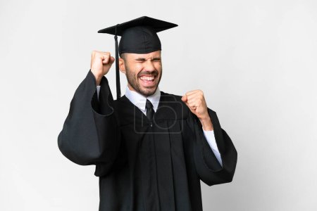 Téléchargez les photos : Jeune diplômé universitaire sur fond blanc isolé célébrant une victoire - en image libre de droit