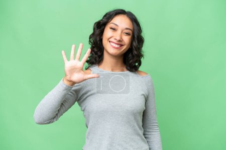 Junge Argentinierin mit isoliertem Hintergrund zählt mit Fingern fünf
