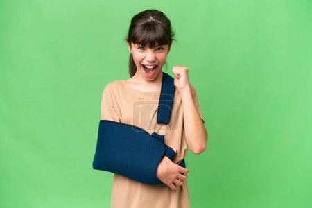 Photo for Little caucasian girl with broken arm and wearing a sling over isolated background celebrating a victory in winner position - Royalty Free Image