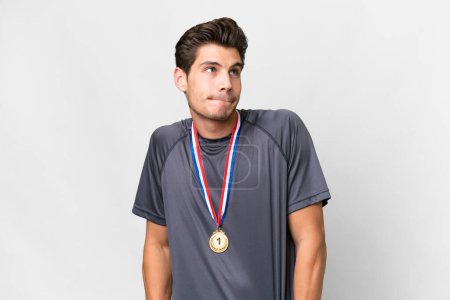 Photo for Young caucasian man with medals over isolated white background making doubts gesture while lifting the shoulders - Royalty Free Image