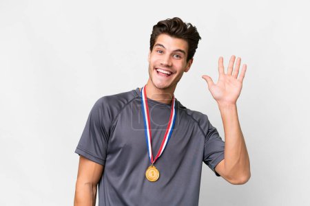 Photo for Young caucasian man with medals over isolated white background saluting with hand with happy expression - Royalty Free Image