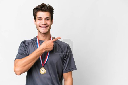 Photo for Young caucasian man with medals over isolated white background pointing to the side to present a product - Royalty Free Image