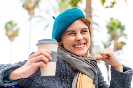 Photo pour Brunette femme tenant un café à emporter à l'extérieur fier et satisfait de soi - image libre de droit