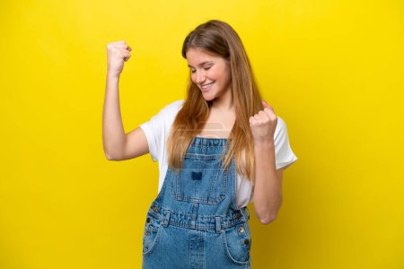 Young caucasian woman isolated on yellow background celebrating a victory