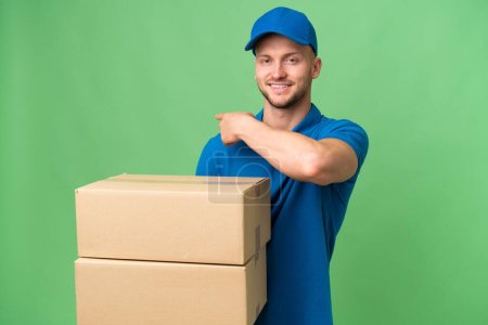 Delivery caucasian man over isolated background pointing back