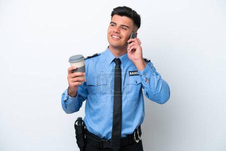 Photo pour Young police caucasian man isolated on white background holding coffee to take away and a mobile - image libre de droit