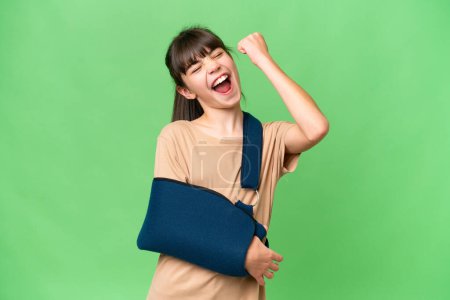 Photo for Little caucasian girl with broken arm and wearing a sling over isolated background celebrating a victory - Royalty Free Image