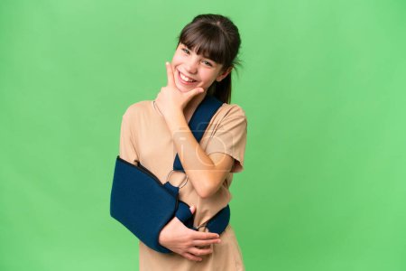 Photo for Little caucasian girl with broken arm and wearing a sling over isolated background happy and smiling - Royalty Free Image
