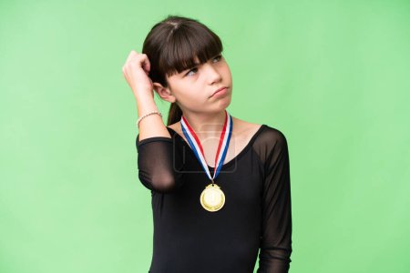 Photo for Little caucasian girl with medals over isolated background having doubts and with confuse face expression - Royalty Free Image
