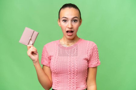 Photo for Young Arab woman holding a wallet over isolated background with surprise and shocked facial expression - Royalty Free Image