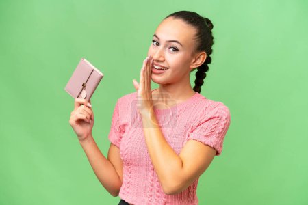 Photo for Young Arab woman holding a wallet over isolated background whispering something - Royalty Free Image