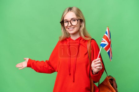 Téléchargez les photos : Young hispanic woman holding an United Kingdom flag over isolated background extending hands to the side for inviting to come - en image libre de droit