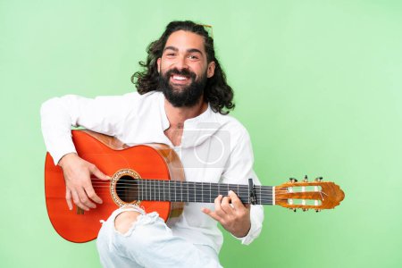 Young man with beard with guitar over isolated chroma key background
