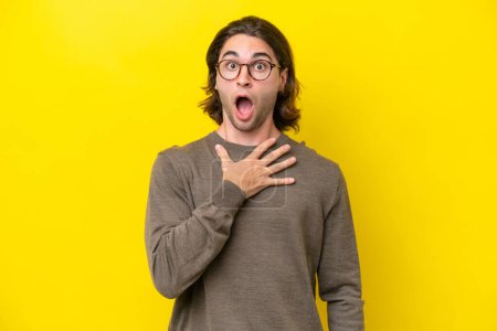 Foto de Caucasian handsome man isolated on yellow background surprised and shocked while looking right - Imagen libre de derechos
