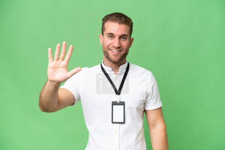Foto de Joven hombre caucásico con tarjeta de identificación aislada sobre fondo de croma verde contando cinco con los dedos - Imagen libre de derechos