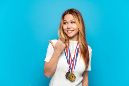Photo for Teenager girl with medals over isolated background pointing to the side to present a product - Royalty Free Image