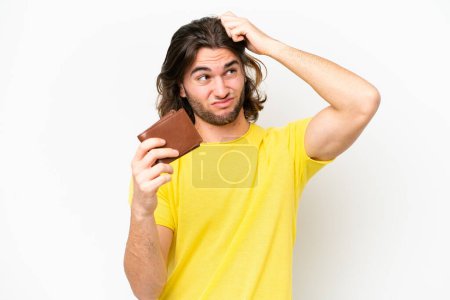 Téléchargez les photos : Jeune homme beau tenant un portefeuille isolé sur fond blanc ayant des doutes et avec une expression du visage confuse - en image libre de droit