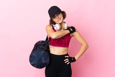 Foto de Mujer deportiva joven con bolsa de deporte sobre fondo aislado que sufre de dolor en el hombro por haber hecho un esfuerzo - Imagen libre de derechos