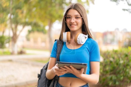 Téléchargez les photos : Adolescente à l'extérieur tenant une tablette - en image libre de droit