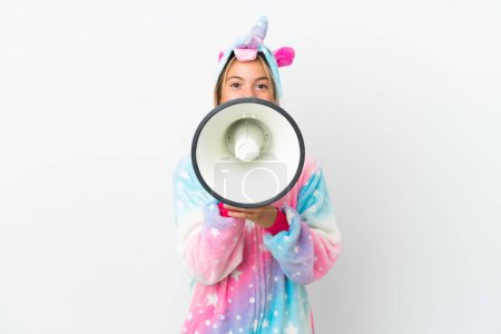 Foto de Niña con pijama de unicornio aislado sobre fondo blanco gritando a través de un megáfono - Imagen libre de derechos