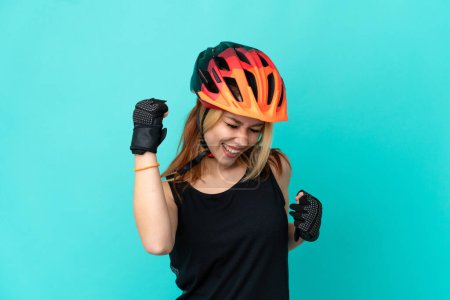 Téléchargez les photos : Jeune fille cycliste sur fond bleu isolé célébrant une victoire - en image libre de droit