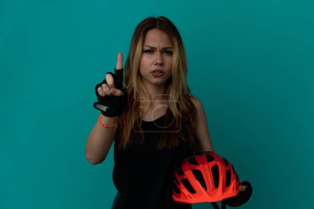 Photo for Young cyclist girl over isolated blue background counting one with serious expression - Royalty Free Image