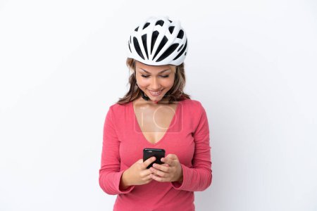 Photo for Young Russian woman wearing a bike helmet isolated on white background sending a message with the mobile - Royalty Free Image