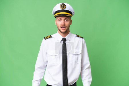 Airplane pilot man over isolated background with surprise facial expression