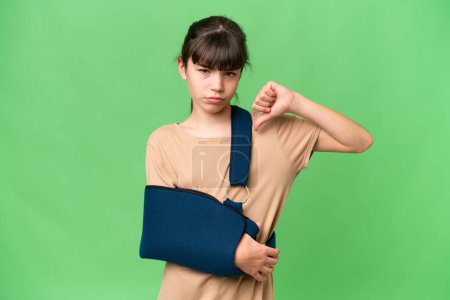Photo for Little caucasian girl with broken arm and wearing a sling over isolated background showing thumb down with negative expression - Royalty Free Image