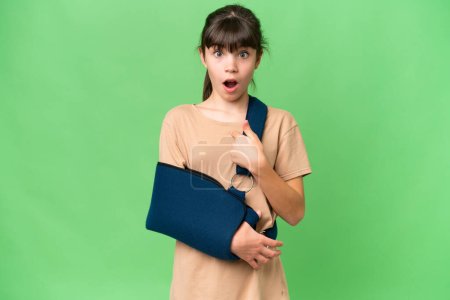 Photo for Little caucasian girl with broken arm and wearing a sling over isolated background with surprise facial expression - Royalty Free Image