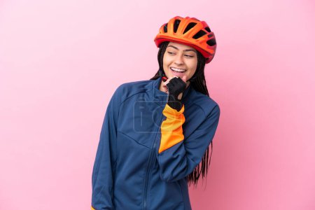 Téléchargez les photos : Adolescente cycliste fille isolé sur fond rose regardant sur le côté et souriant - en image libre de droit