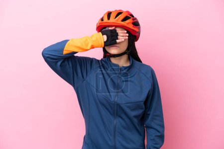 Téléchargez les photos : Adolescente cycliste fille isolée sur fond rose couvrant les yeux par les mains. Je ne veux pas voir quelque chose - en image libre de droit