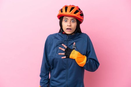 Téléchargez les photos : Adolescente cycliste fille isolé sur fond rose surpris et choqué tout en regardant à droite - en image libre de droit