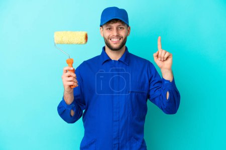 Painter caucasian man isolated on blue background pointing up a great idea