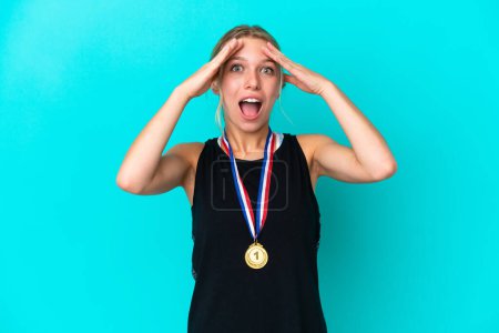 Photo for Young caucasian woman with medals isolated on blue background with surprise expression - Royalty Free Image