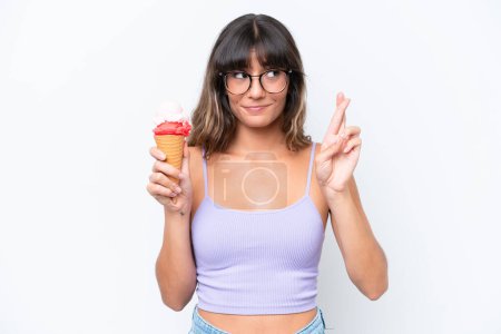 Photo for Young caucasian woman with a cornet ice cream over isolated white background with fingers crossing and wishing the best - Royalty Free Image