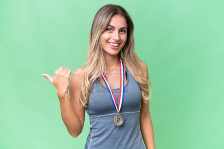 Photo for Young pretty sport Uruguayan woman with medals over isolated background pointing to the side to present a product - Royalty Free Image