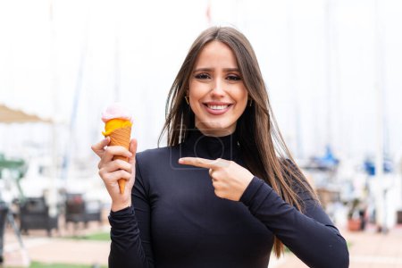 Foto de Joven mujer bonita con un helado de corneta al aire libre con expresión facial sorpresa - Imagen libre de derechos