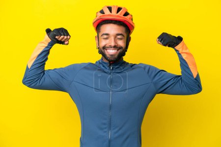 Photo for Young cyclist Brazilian man isolated on yellow background doing strong gesture - Royalty Free Image