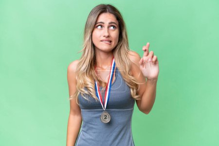 Photo for Young pretty sport Uruguayan woman with medals over isolated background with fingers crossing and wishing the best - Royalty Free Image