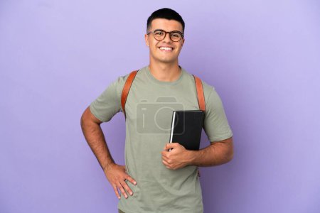 Handsome student man over isolated background posing with arms at hip and smiling