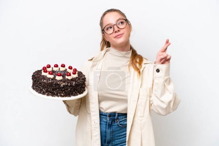 Photo for Young caucasian woman holding a Birthday cake isolated on white background with fingers crossing and wishing the best - Royalty Free Image