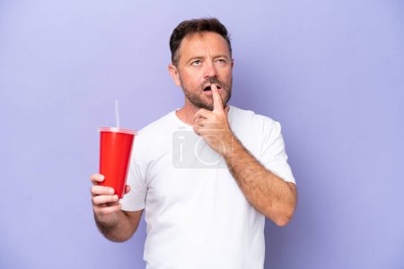 Foto de Hombre caucásico de mediana edad sosteniendo soda aislada sobre fondo púrpura teniendo dudas mientras mira hacia arriba - Imagen libre de derechos