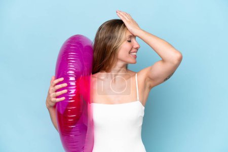 Téléchargez les photos : Jeune femme blonde en maillot de bain tenant donut gonflable isolé sur fond bleu a réalisé quelque chose et l'intention de la solution - en image libre de droit