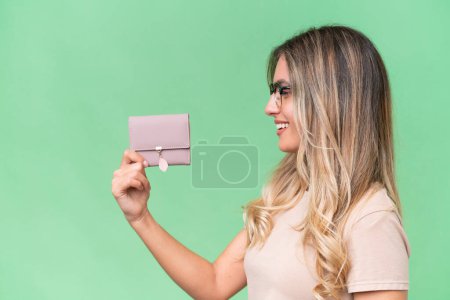 Photo for Young Uruguayan woman holding a wallet over isolated background with happy expression - Royalty Free Image