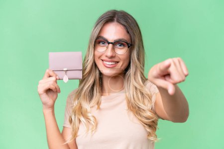 Photo for Young Uruguayan woman holding a wallet over isolated background points finger at you with a confident expression - Royalty Free Image
