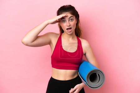 Téléchargez les photos : Jeune femme sportive allant à des cours de yoga tout en tenant un tapis avec expression surprise - en image libre de droit