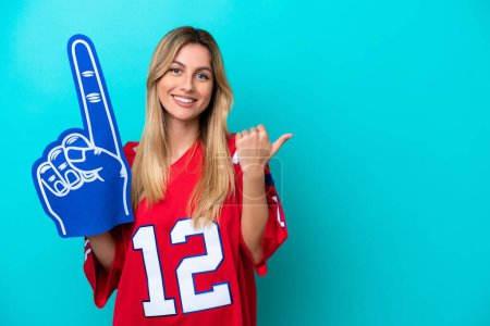 Photo for Uruguayan sports fan woman isolated on blue background pointing to the side to present a product - Royalty Free Image